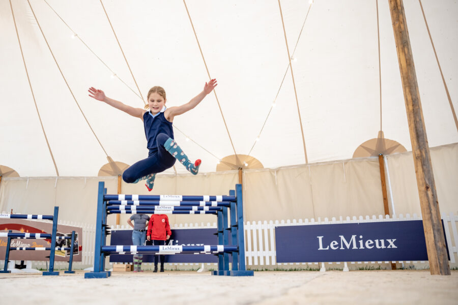 child jumping over hobby horse jump